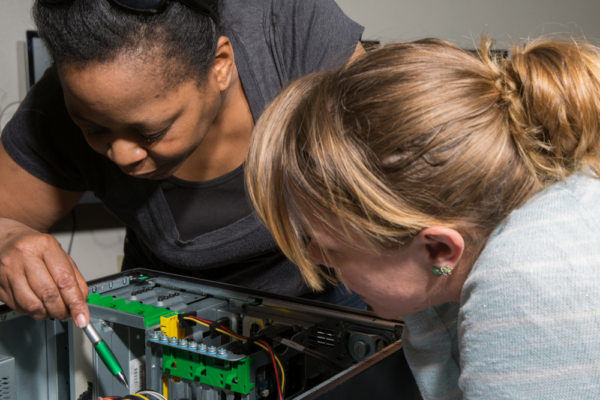 Two women study computer hardware