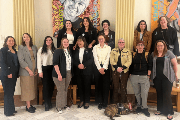 A group of a dozen women stand in the Colorado State Capitol.