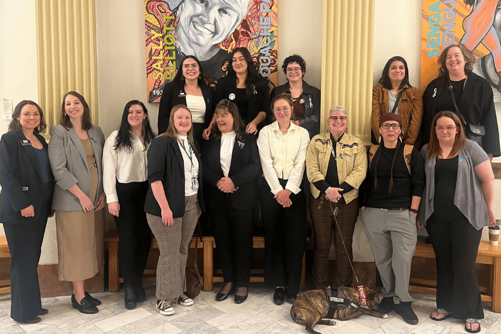 A group of a dozen women stand in the Colorado State Capitol.