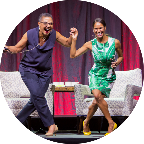 Lauren Y. Casteel and Misty Copeland laugh onstage while holding hands and curtsying at 2016 Annual Luncheon