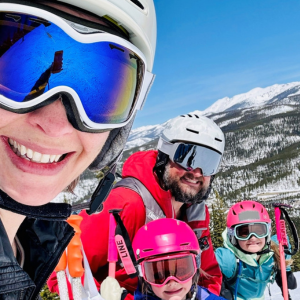 A woman in ski goggles and helmet with a man and two children on a ski mountain.