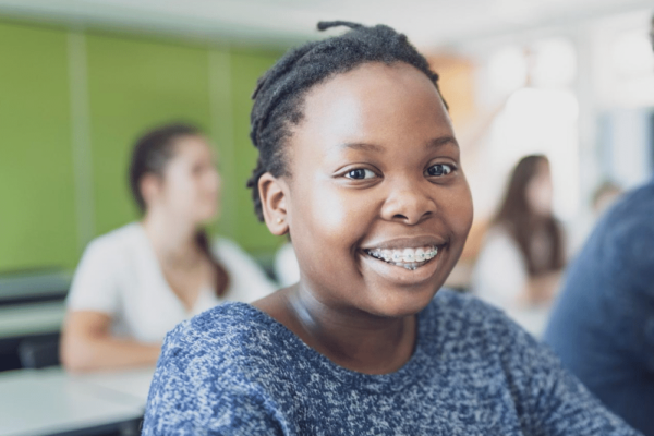 a young Black girl smiles in a classroom
