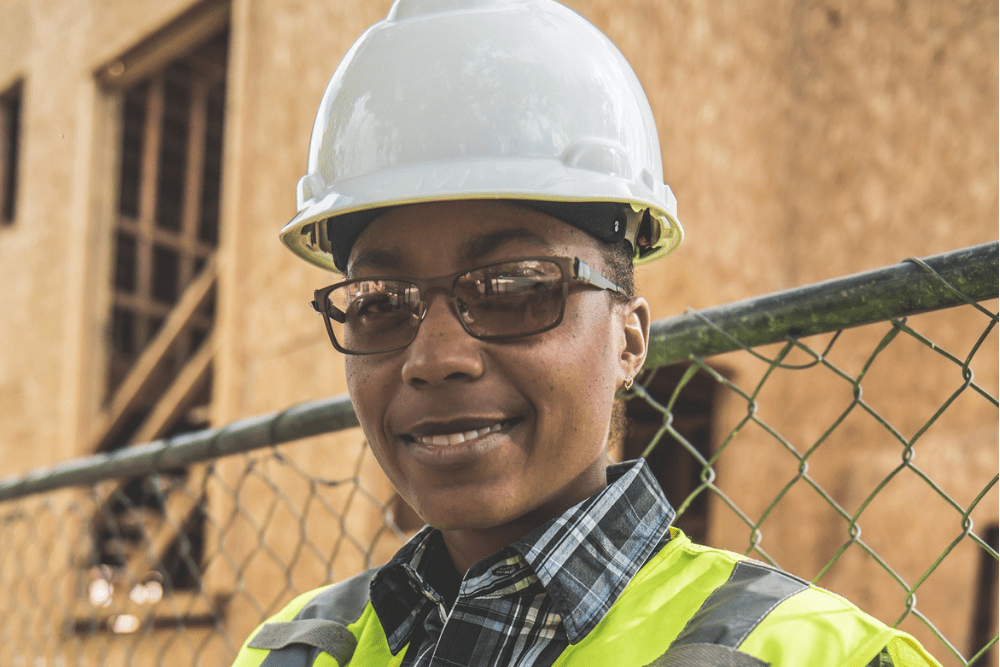 A woman in a hard hat smiles at the camera.