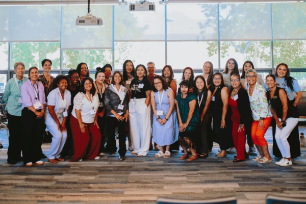 A group of 30 or so women of color smile for the camera.