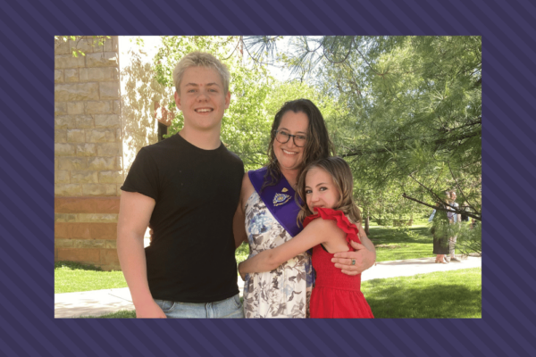 Hayley in a graduation stole and her two oldest children smile with their arms around each other