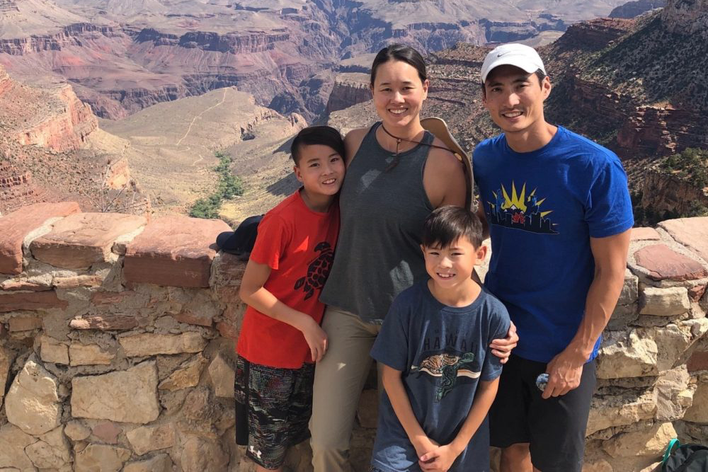 A family of four stands in front of the Grand Canyon.